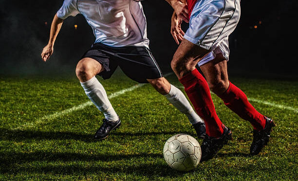 Two soccer players challenging for the ball, low angle view.